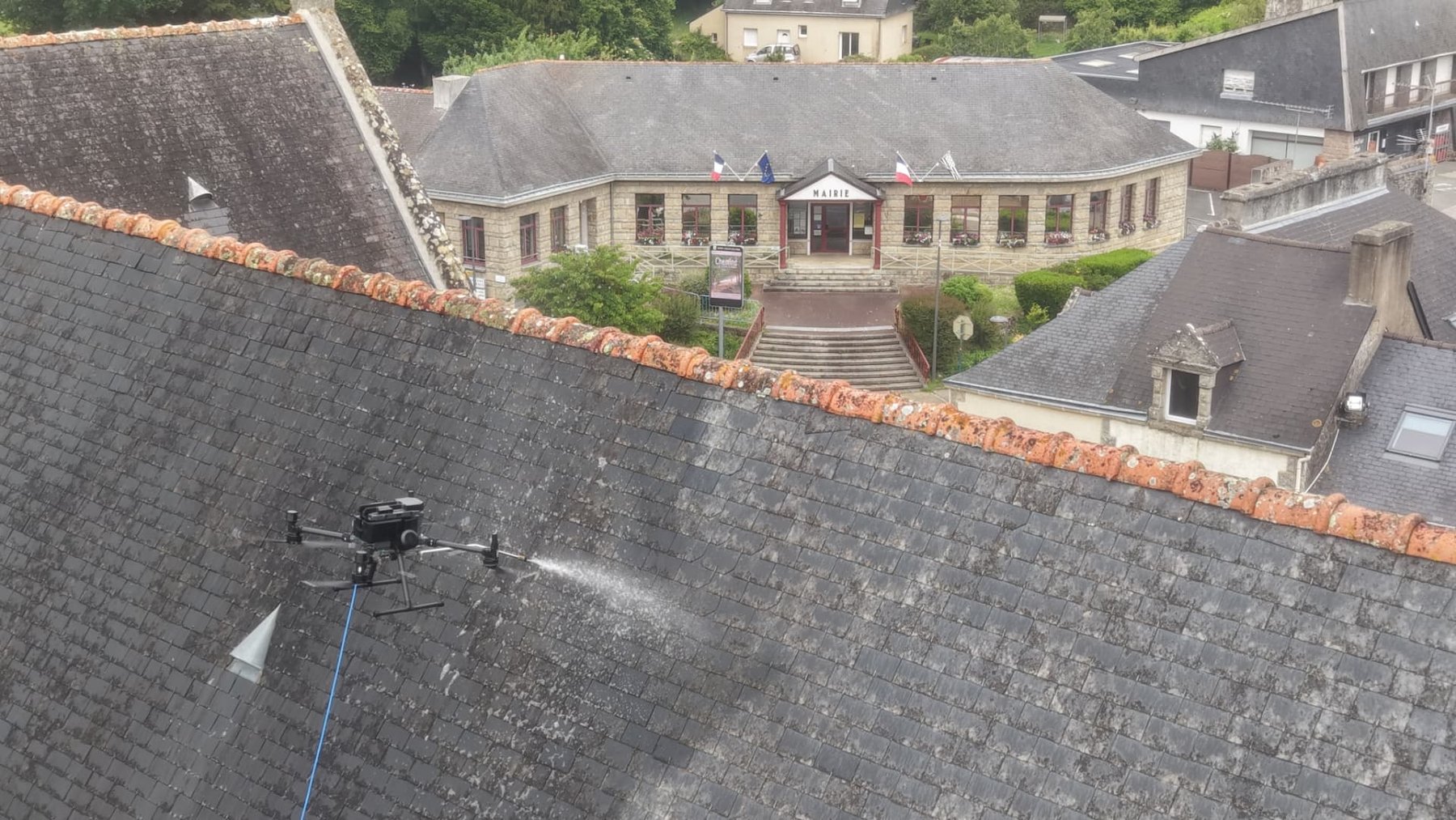 Drone ALR Drones traitant une toiture d'ardoise avec la mairie de Saint-Jacut-les-Pins (56) en arrière-plan