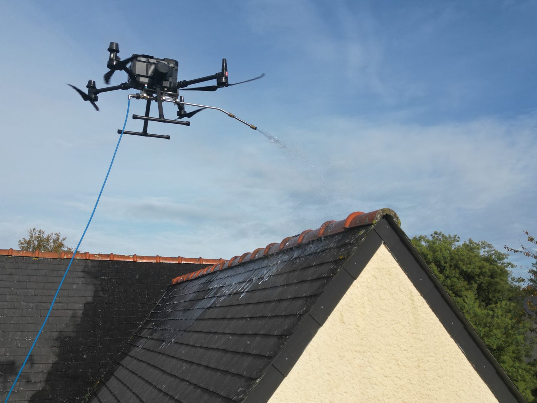 DJI Matrice 350 RTK d'ALR Drones en vol, lance de pulvérisation déployée au-dessus d'une toiture en ardoise